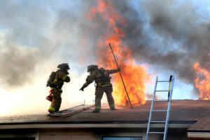 Firefighters on a Roof Putting Out a Nearby Fire